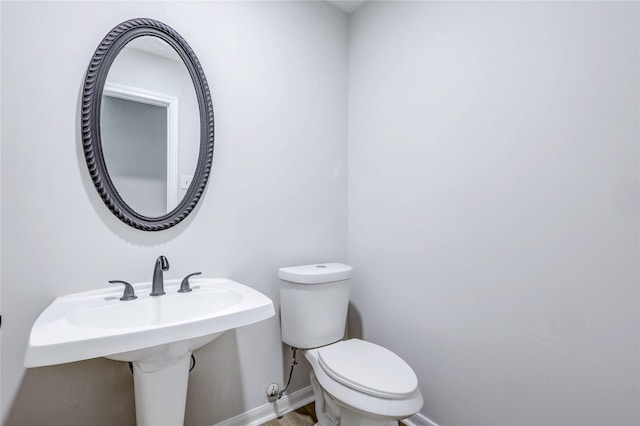 half bath featuring a sink, wood finished floors, toilet, and baseboards