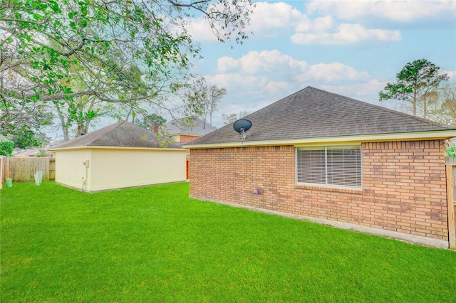 rear view of property with a yard, a shingled roof, fence, and brick siding