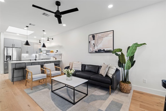 living area with a skylight, visible vents, light wood finished floors, and recessed lighting