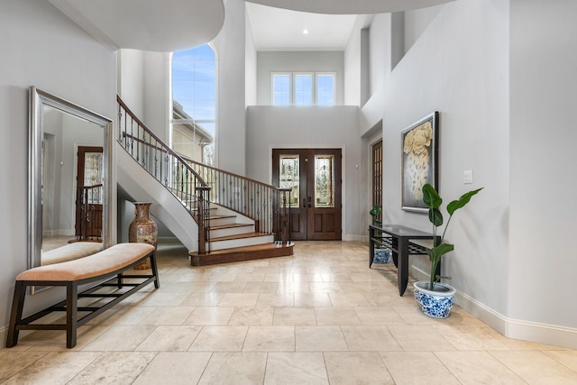 entrance foyer featuring a towering ceiling, stairs, and baseboards