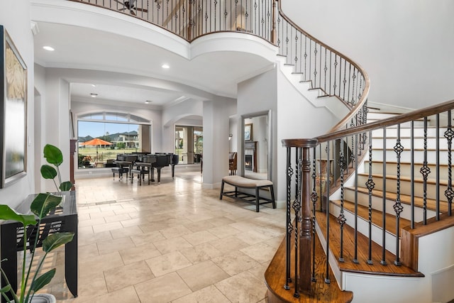 entrance foyer featuring stairway, baseboards, arched walkways, and ornamental molding