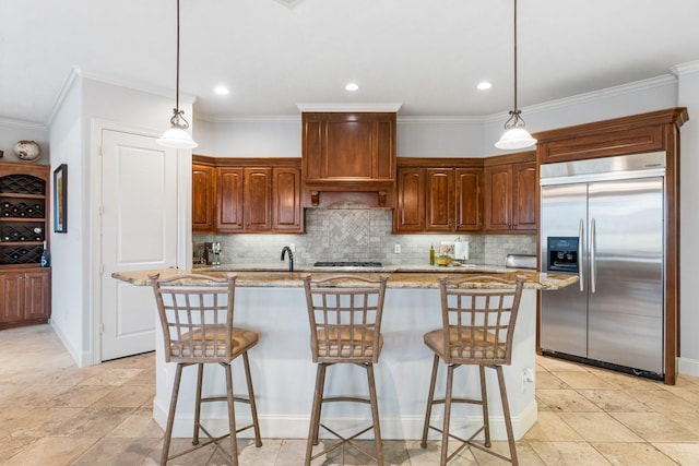 kitchen featuring built in fridge, hanging light fixtures, backsplash, and extractor fan