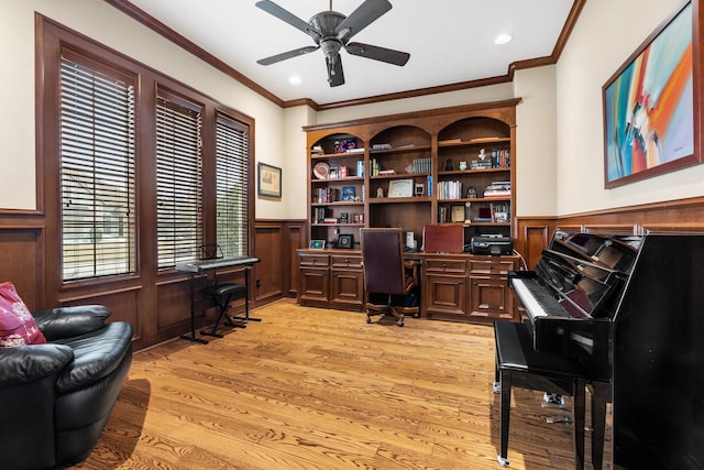 office area with wainscoting, ornamental molding, light wood finished floors, and built in study area