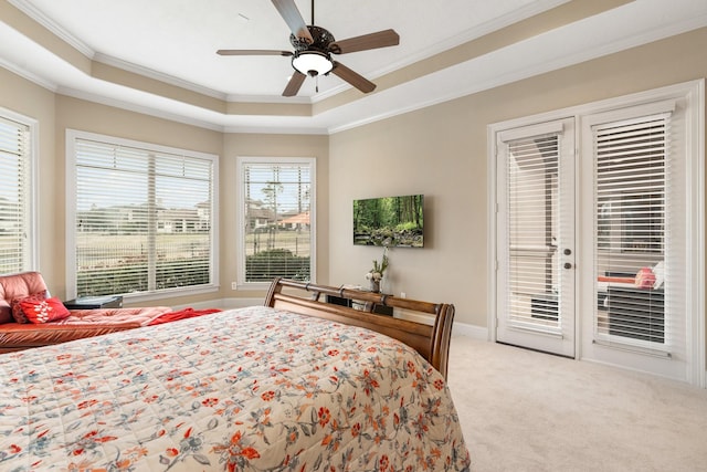 bedroom with access to exterior, a tray ceiling, ornamental molding, and light colored carpet