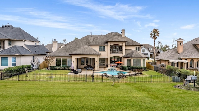 rear view of house with a lawn, a chimney, a fenced backyard, and a pool with connected hot tub