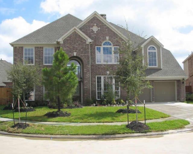 view of front of property featuring driveway, brick siding, and a front yard