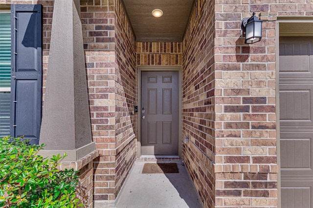 property entrance featuring a garage and brick siding