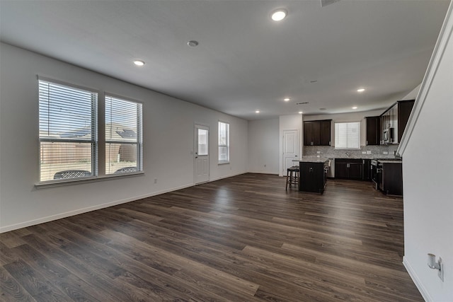 unfurnished living room with baseboards, dark wood-style flooring, and recessed lighting