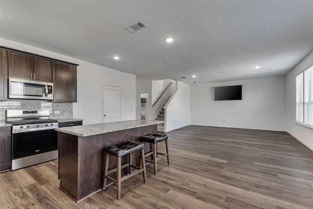 kitchen with a center island, a breakfast bar area, visible vents, appliances with stainless steel finishes, and dark brown cabinets