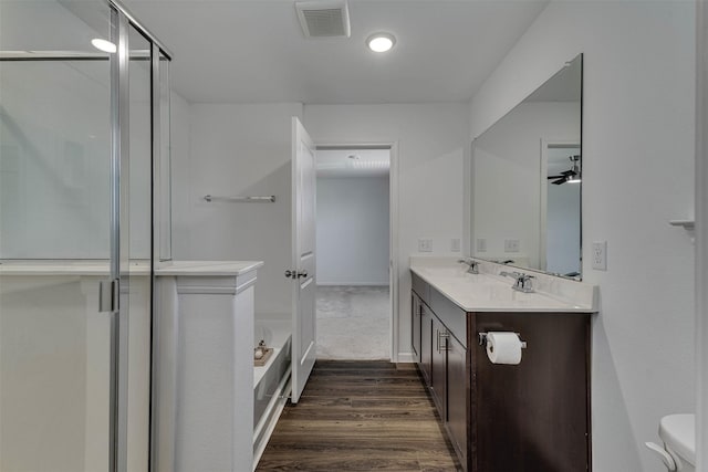 full bathroom featuring double vanity, visible vents, a bath, wood finished floors, and a sink