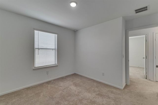 empty room featuring baseboards, visible vents, and light colored carpet