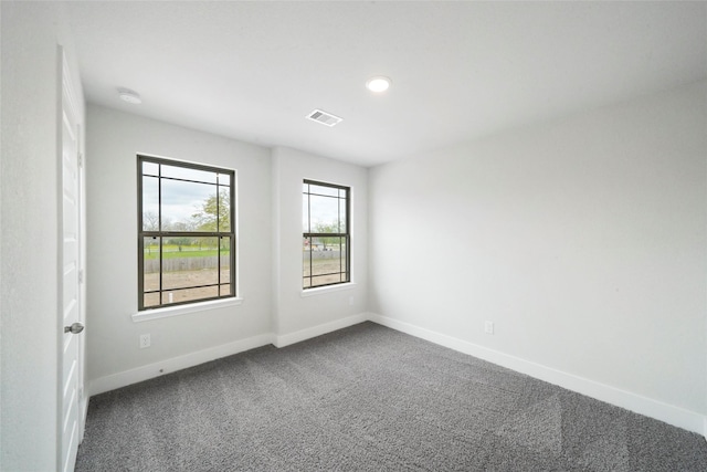 empty room featuring carpet, visible vents, and baseboards