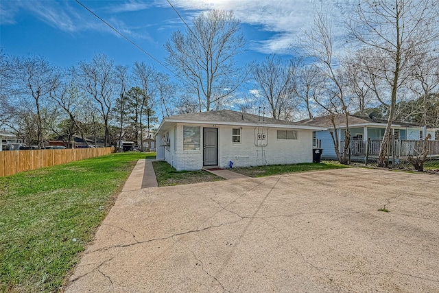 view of front of home with a front yard, fence, and brick siding