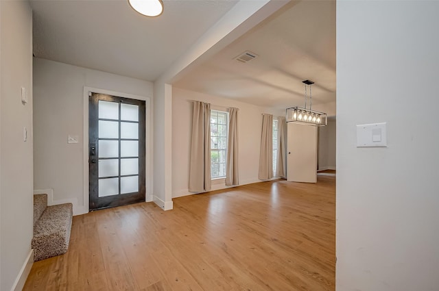 foyer featuring baseboards, visible vents, light wood finished floors, and stairs