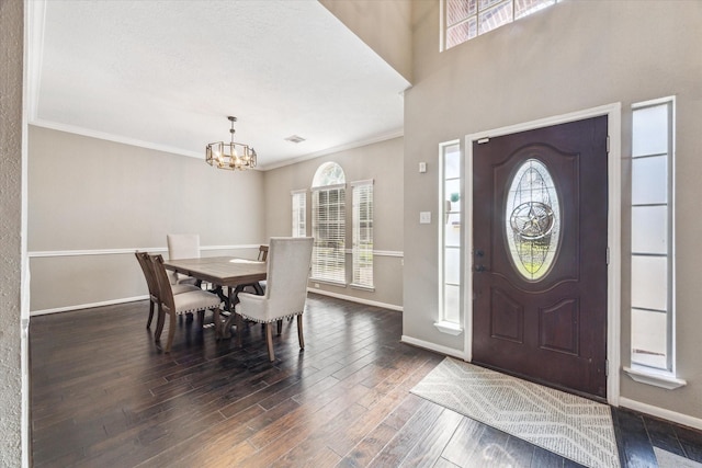 foyer entrance with plenty of natural light, dark wood finished floors, an inviting chandelier, and baseboards