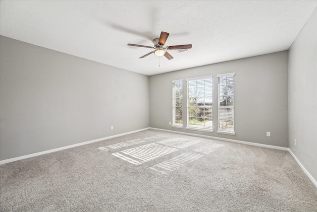 carpeted spare room with a textured ceiling, baseboards, and a ceiling fan