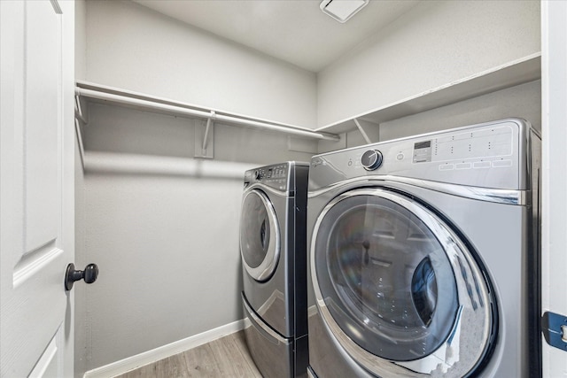 laundry room with laundry area, washer and clothes dryer, light wood-style flooring, and baseboards