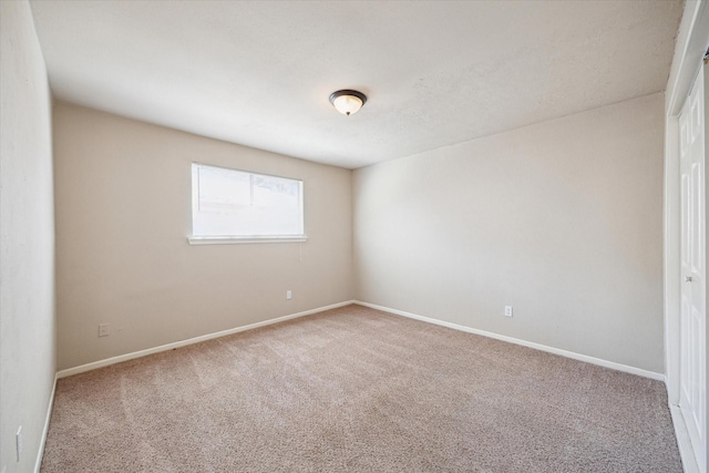 spare room with baseboards and carpet flooring