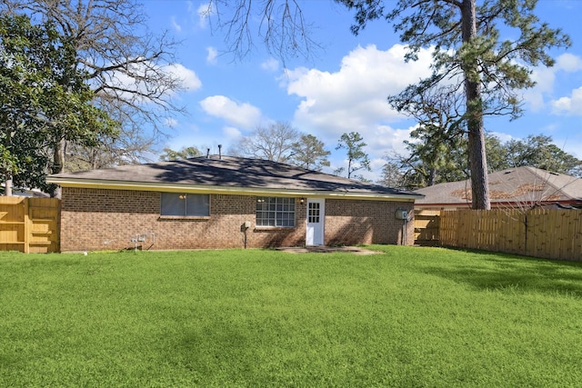 back of property featuring brick siding, a lawn, and fence