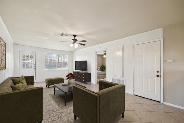 living room featuring light tile patterned flooring, visible vents, baseboards, and a ceiling fan