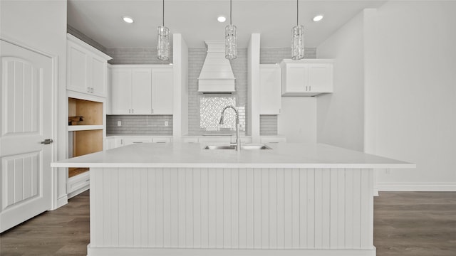 kitchen featuring a kitchen island with sink, light countertops, a sink, and decorative light fixtures