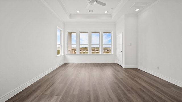 unfurnished room with a wealth of natural light, dark wood-style flooring, crown molding, and a tray ceiling