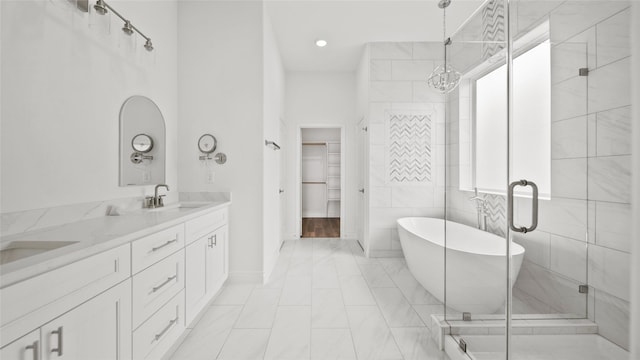 bathroom with double vanity, a soaking tub, an inviting chandelier, a sink, and a shower stall