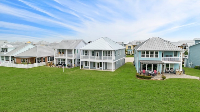 back of house with a yard, a residential view, a patio, and a balcony