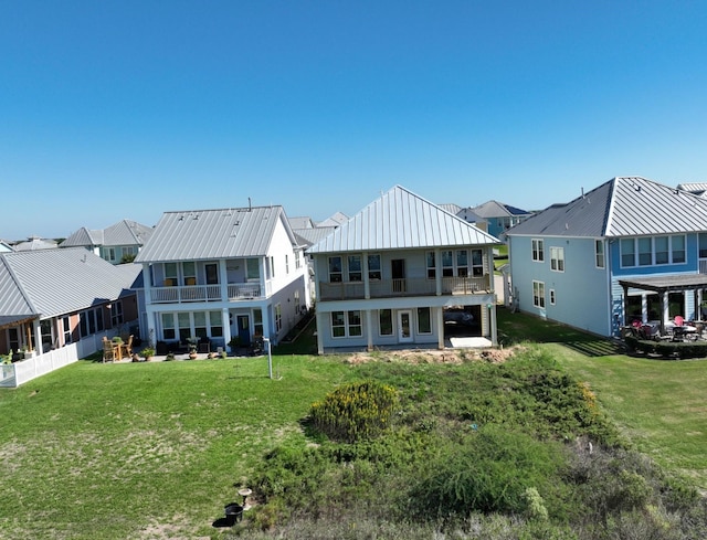 rear view of property with a residential view, metal roof, and a yard