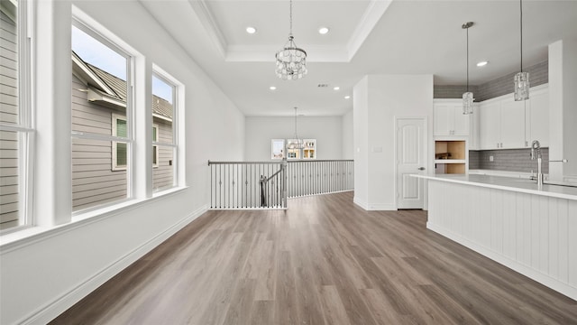 kitchen featuring light countertops, a raised ceiling, white cabinetry, and an inviting chandelier