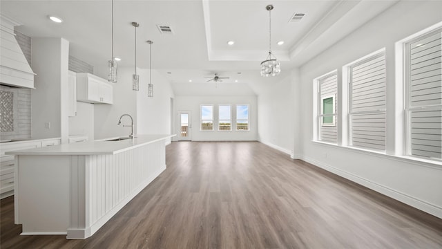 kitchen featuring decorative light fixtures, light countertops, open floor plan, a sink, and an island with sink