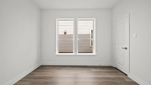 spare room featuring baseboards and wood finished floors