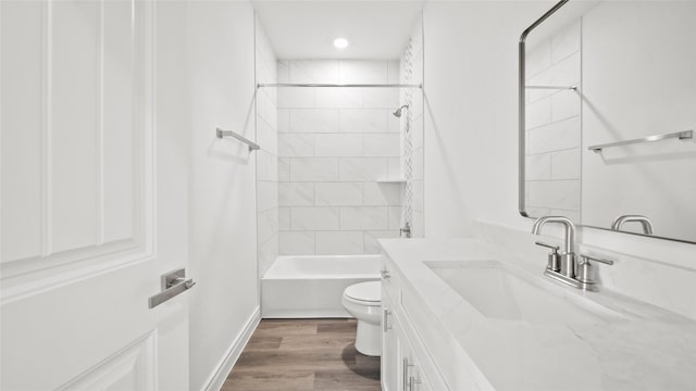 bathroom with baseboards, toilet, shower / bathtub combination, wood finished floors, and vanity