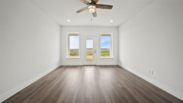 empty room featuring ceiling fan, baseboards, and dark wood finished floors