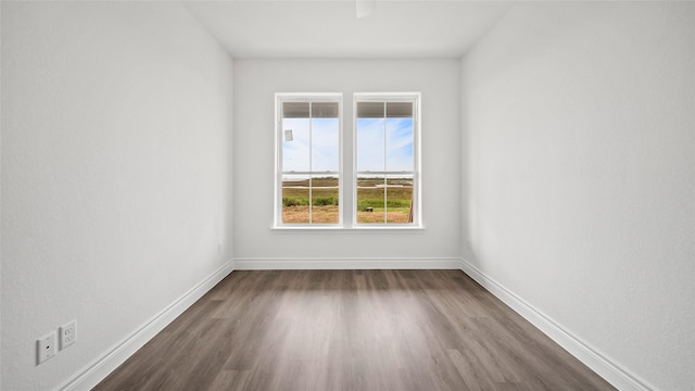 unfurnished room featuring dark wood-style flooring and baseboards