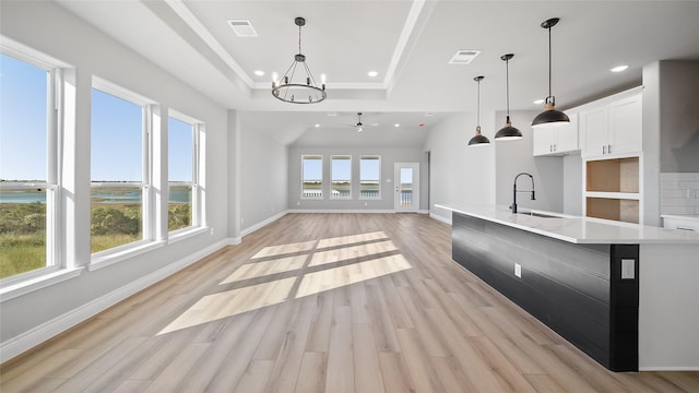 kitchen with a sink, visible vents, white cabinetry, light countertops, and decorative light fixtures