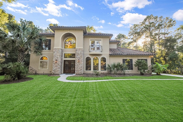 mediterranean / spanish-style home with french doors, a front lawn, and a tile roof