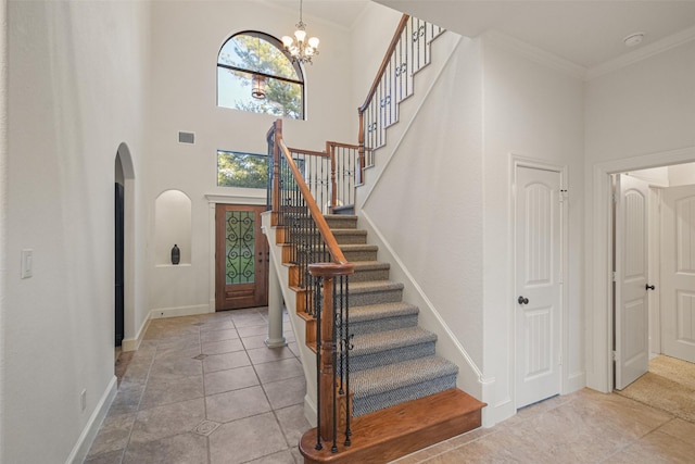 entrance foyer featuring arched walkways, visible vents, a towering ceiling, baseboards, and ornamental molding