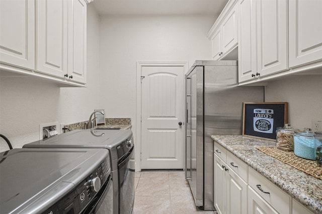 washroom with light tile patterned floors, cabinet space, and washer and dryer