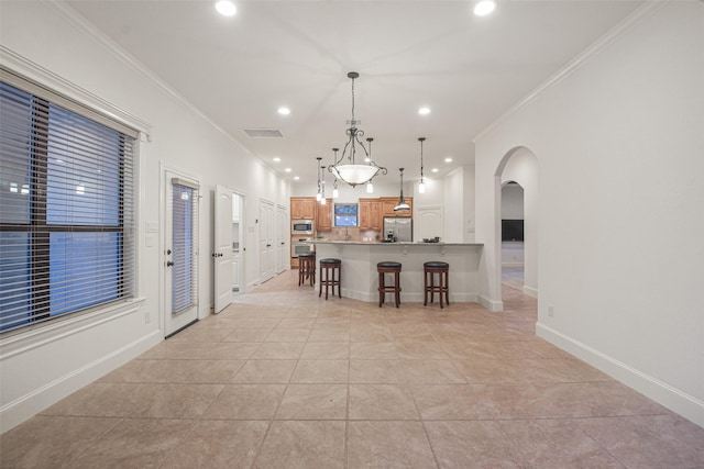 kitchen featuring a breakfast bar, arched walkways, stainless steel appliances, visible vents, and hanging light fixtures