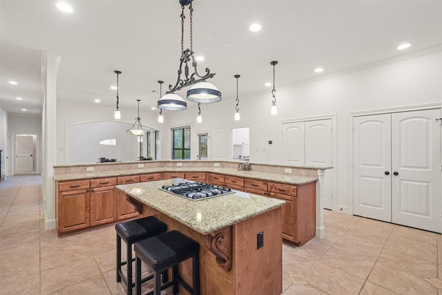 kitchen featuring pendant lighting, a breakfast bar area, a spacious island, stainless steel gas stovetop, and light stone countertops