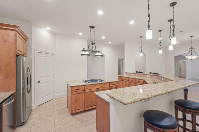 kitchen featuring stainless steel appliances, a breakfast bar, decorative light fixtures, and a spacious island