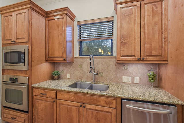 kitchen with brown cabinets, decorative backsplash, stainless steel appliances, and a sink