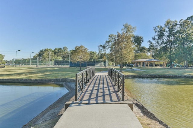 dock area featuring a gazebo, a lawn, a water view, and fence