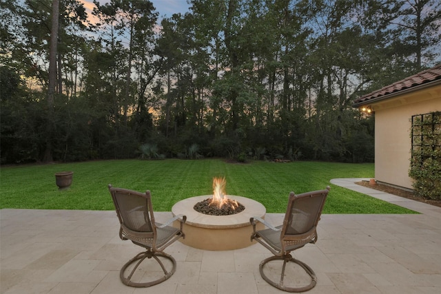 patio terrace at dusk featuring a yard and a fire pit