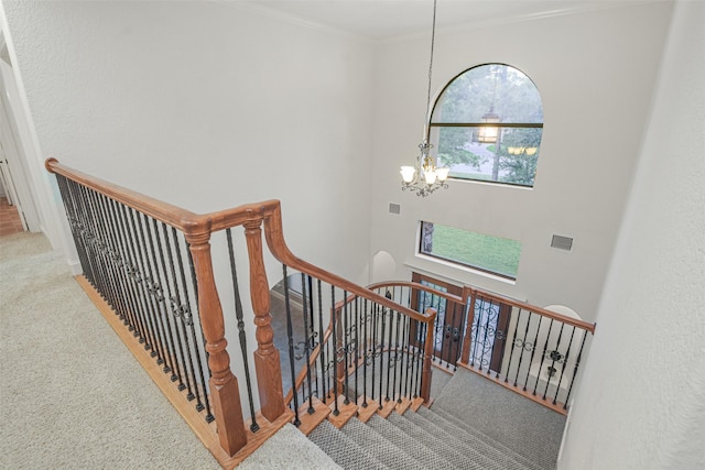 stairway featuring visible vents, crown molding, carpet flooring, and an inviting chandelier