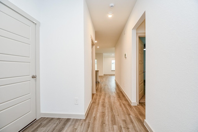 corridor with light wood-type flooring and baseboards