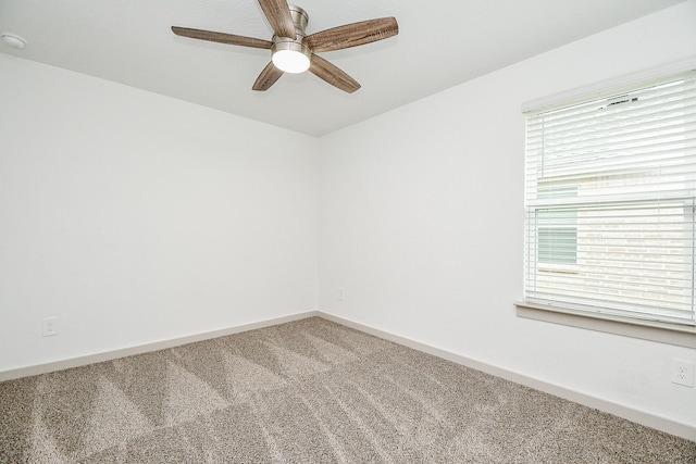 carpeted spare room featuring ceiling fan and baseboards