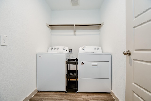 laundry room with laundry area, visible vents, baseboards, light wood-style floors, and washer and dryer