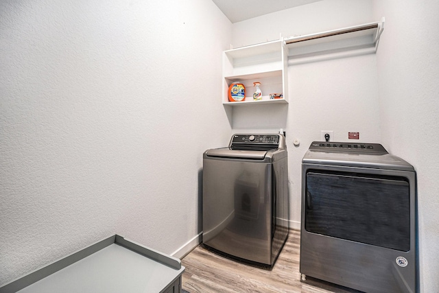 laundry area with laundry area, baseboards, light wood finished floors, and washing machine and clothes dryer